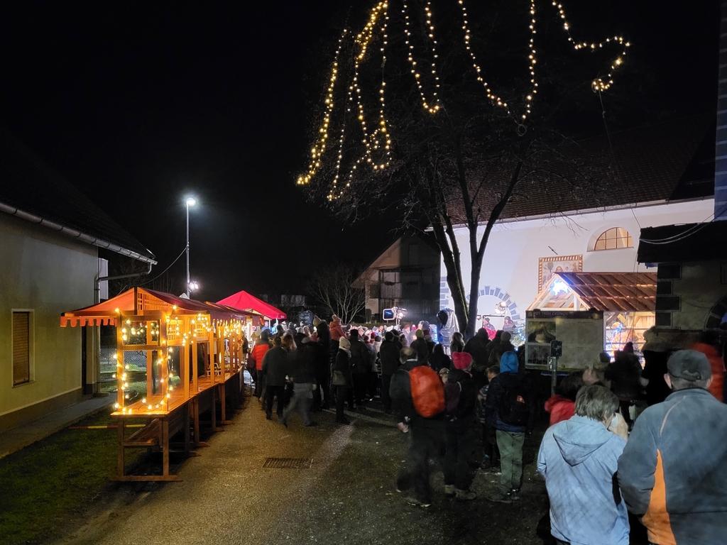 Z lučkami osvetljene stojnice in drevo v ozadju jaslice in cerkev, arhiv inPlaninec